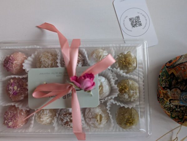 A box of handmade rose amaretti cookies topped with rose petals, arranged for gifting with soft floral accents.