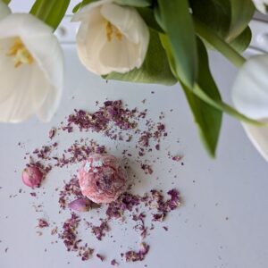 Soft rose amaretti cookies topped with dried rose petals, arranged on a white surface with delicate floral accents.